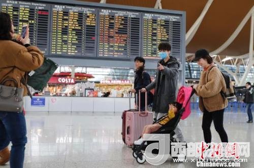 旅客帶著孩子前往辦票柜臺辦理登機手續(xù)?！∫罅⑶?攝