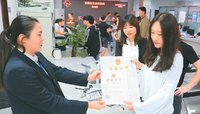 河北省承德市網(wǎng)絡(luò)代購經(jīng)營者陳晨(右)從工作人員手中接過帶有統(tǒng)一社會(huì)信用代碼的營業(yè)執(zhí)照。 劉環(huán)宇攝(人民圖片)