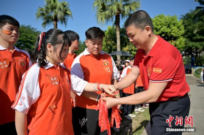 資料圖：廣西華僑實(shí)驗(yàn)高中的教師為高三學(xué)子系上紅絲帶，盼望學(xué)子高考必勝。 俞靖 攝